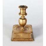 AN EARLY BRASS CANDLESTICK on a square base. 5ins high.