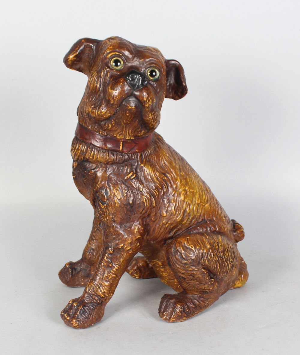 A 19TH CENTURY MOULDED POTTERY MODEL OF A SEATED DOG, with amusing expression and glass eyes.