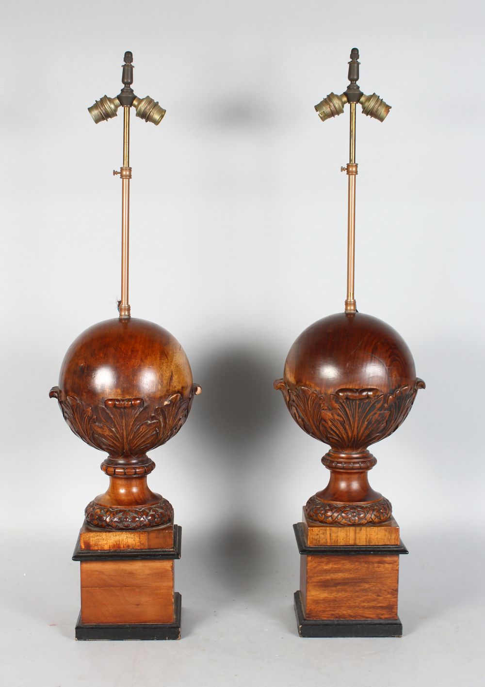 A PAIR OF 20TH CENTURY CARVED WOOD SPHERICAL TABLE LAMPS, on square plinths. 2ft 6ins high (