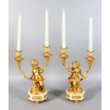 AFTER CLODION A GOOD PAIR OF ORMOLU AND WHITE MARBLE TWO BRANCH CANDLESTICKS, as cupids holding