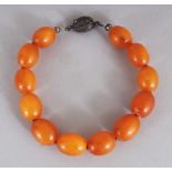 AN AMBER BRACELET, with a silver metal clasp, weighing approx. 12gm, composed of oval beads, approx.