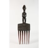 A CARVED TRIBAL COMB, the handle as a woman with scars. 11ins.