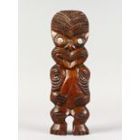 A MAORI CARVED WOOD STANDING FIGURE with mother-of-pearl eyes. 14ins long.