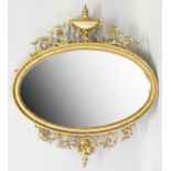 A VICTORIAN COMPOSITION GILT ADAM DESIGN OVAL MIRROR, with urn finial and scrolls. 3ft long x 3ft