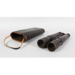 A PAIR OF EARLY 20TH CENTURY LONG MILITARY STYLE BINOCULARS, in a leather case. 11ins long.