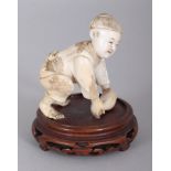 A JAPANESE MEIJI PERIOD IVORY OKIMONO OF A BOY, together with a fixed wood stand, the boy kneeling