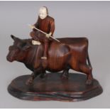 AN EARLY 20TH CENTURY JAPANESE IVORY & WOOD GROUP OF A MAN RIDING A BULL, the base with an