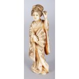 A JAPANESE MEIJI PERIOD IVORY OKIMONO OF A STANDING LADY, holding an open fan, 4in high.