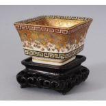 A SUPERB SMALL JAPANESE SATSUMA SQUARE POT, with key pattern decoration, on a carved stand. 1.5ins.