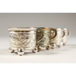 A SMALL SET OF FOUR ENGRAVED CUPS, on three ball feet.