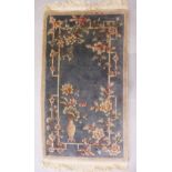 A CHINESE RUG, blue ground decorated with a vase of flowers and foliage. 5ft 6ins x 3ft 0ins.