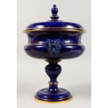 A LARGE SEVRES PEDESTAL BOWL AND COVER, with satyr mask handles and lapis style glaze. 17ins high.