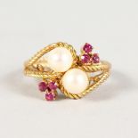 A GOLD RING, with crossover pearls and flower head.