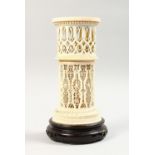 A 19TH CENTURY EUROPEAN CARVED AND PIERCED IVORY STAND, on a circular wooden base. 7.5ins high