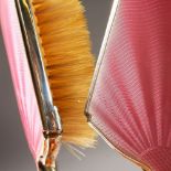 A PINK ENAMEL AND SILVER DRESSING TABLE SET, hand mirror, powder bowl, comb and two brushes.