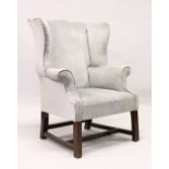 A GEORGE III MAHOGANY FRAMED WING ARMCHAIR, upholstered in a pale blue fabric, on stretchered square