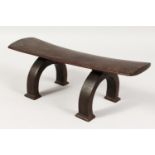 A TONGA HEADREST, plain top on curving legs. 16ins wide.