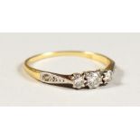 A GOLD THREE STONE DIAMOND RING.