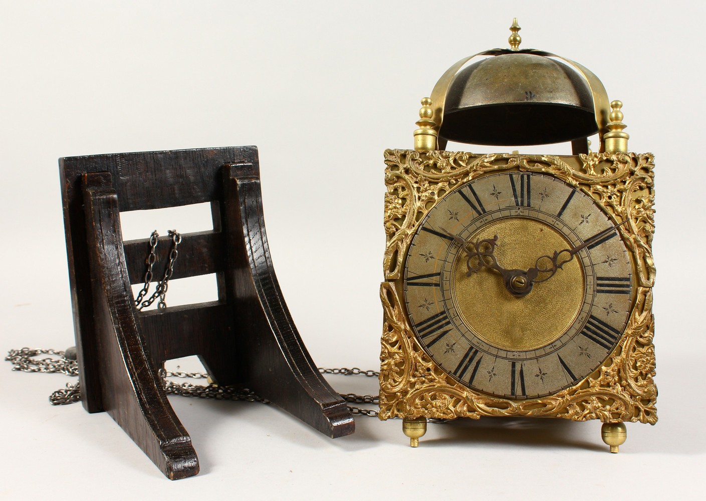 A GOOD BRASS LANTERN CLOCK, with bell, square face and silvered ring, 6.25-inch dial, on a wooden