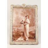 A SILVER PHOTOGRAPH FRAME, with embossed rococo style frame, marks worn. 17ins high x 11.5ins wide.