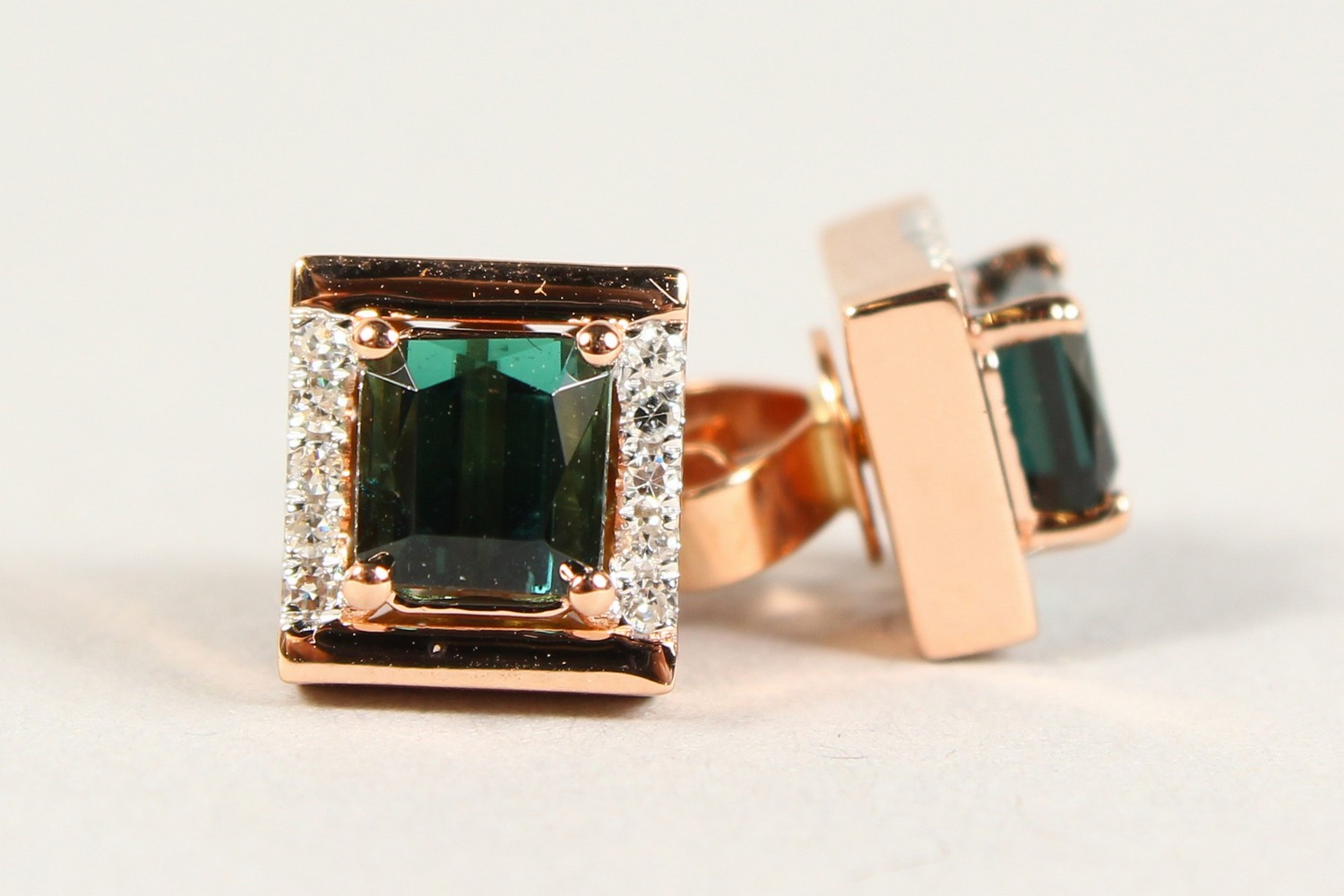 A PAIR OF 14CT ROSE GOLD EMERALD CUT GREEN TOURMALINE EAR STUDS.