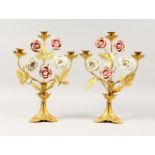 A PAIR OF GILT METAL THREE-LIGHT CANDLESTICKS, with porcelain roses. 14ins high.