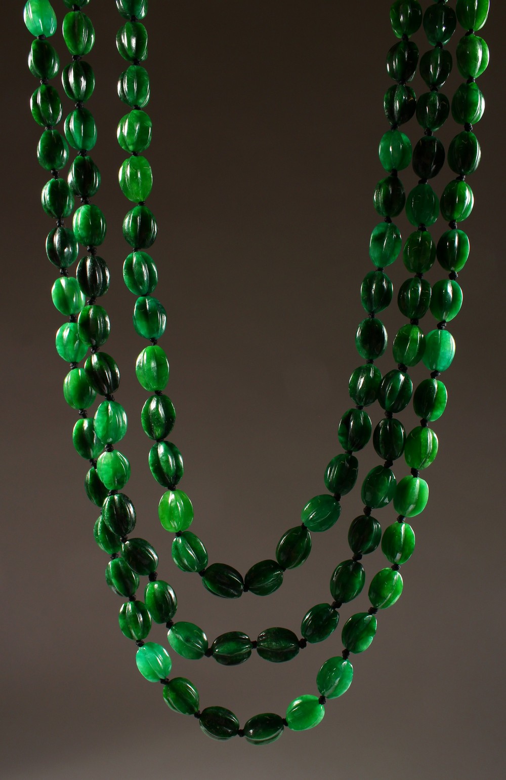 A VERY GOOD TRIPLE ROW JADE NECKLACE, with 18ct gold clasp.