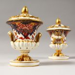 A SMALL PAIR OF CROWN DERBY ROUGE DE FER TWO-HANDLED URNS AND COVERS. Mark in Red. 5ins high.