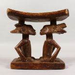 A TRIBAL HEADREST, the base covered with a pair of seated figures. 7.5ins wide.