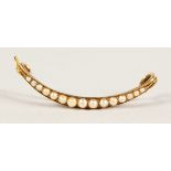 AN EDWARDIAN GOLD SEED PEARL SET CRESCENT BROOCH.