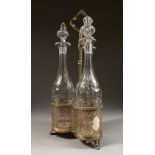 A GOOD SET OF THREE CUT GLASS TALL DECANTERS AND STOPPERS, in a pierced mesh plated stand, on