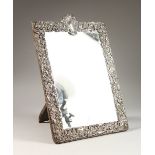 A SILVER FRAMED DRESSING TABLE MIRROR, the frame with embossed and chased decoration, depicting