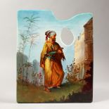 AN ARTISTS PORCELAIN PALETTE, painted with a standing Arab male, beside a building. 10.5ins x 9ins.