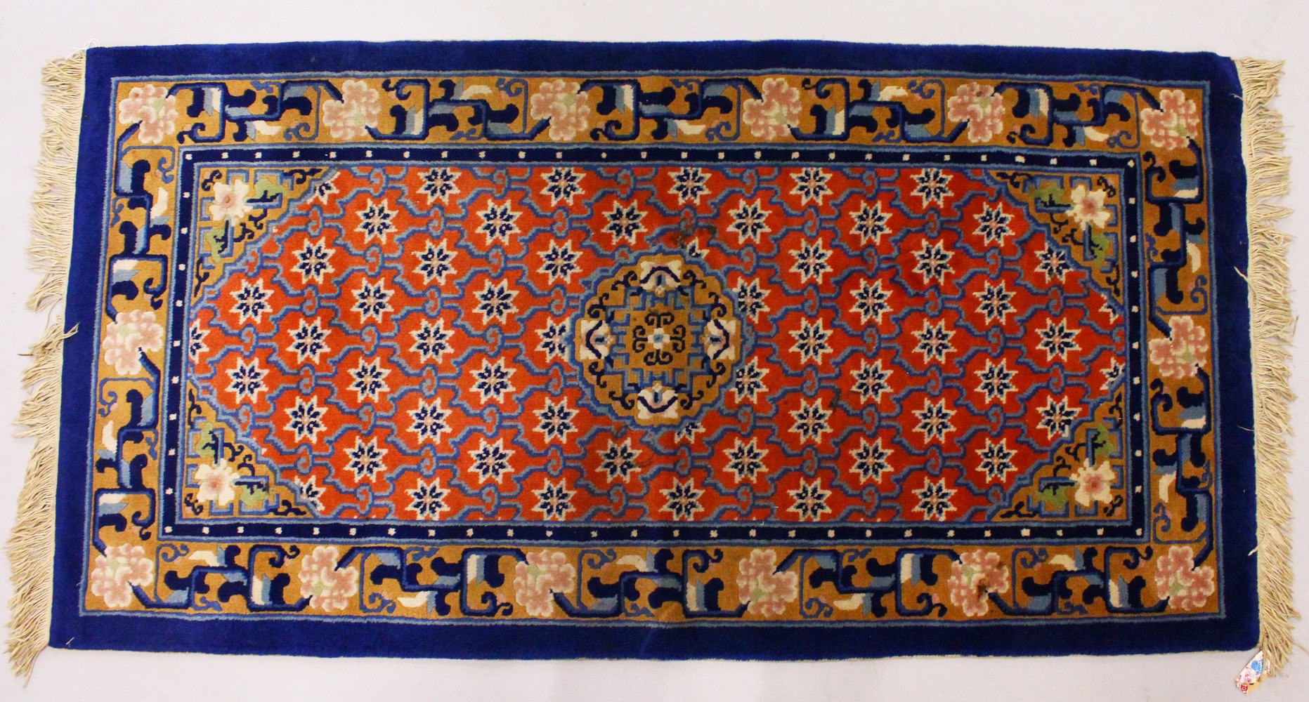 A CHINESE RUG, with red ground, motifs and blue border. 4ft 9ins x 2ft 4ins.