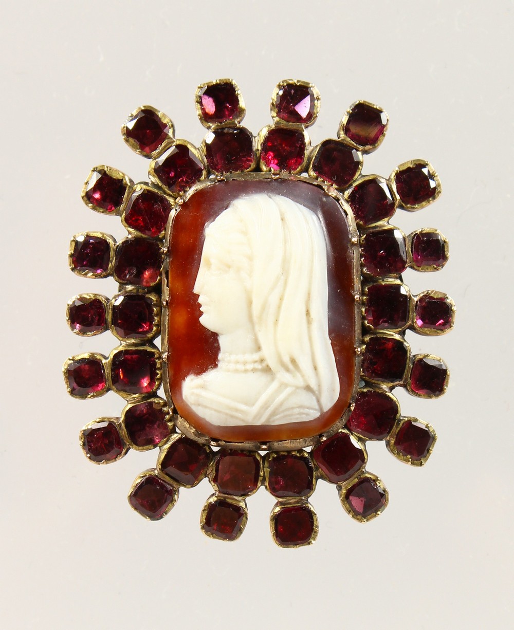 A GOOD GEORGIAN HARDSTONE CAMEO, with garnet surround.