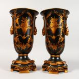 A PAIR OF BLACK PORCELAIN TOLEWARE TYPE URNS ON STANDS. 13ins high.