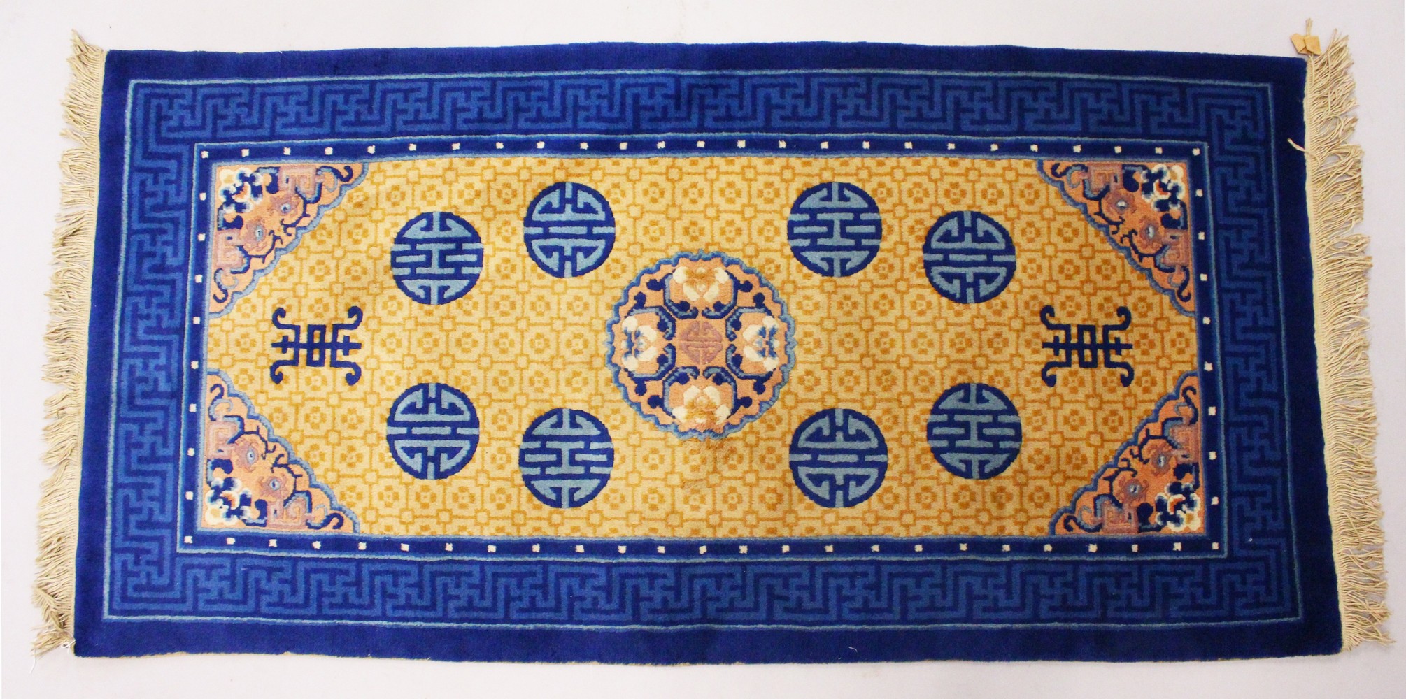 A CHINESE RUG, with beige ground, central motif and eight blue motifs. 5ft x 2ft 3ins.