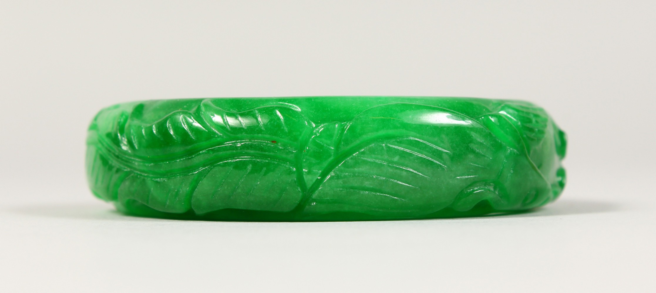 A CARVED APPLE JADE BANGLE.