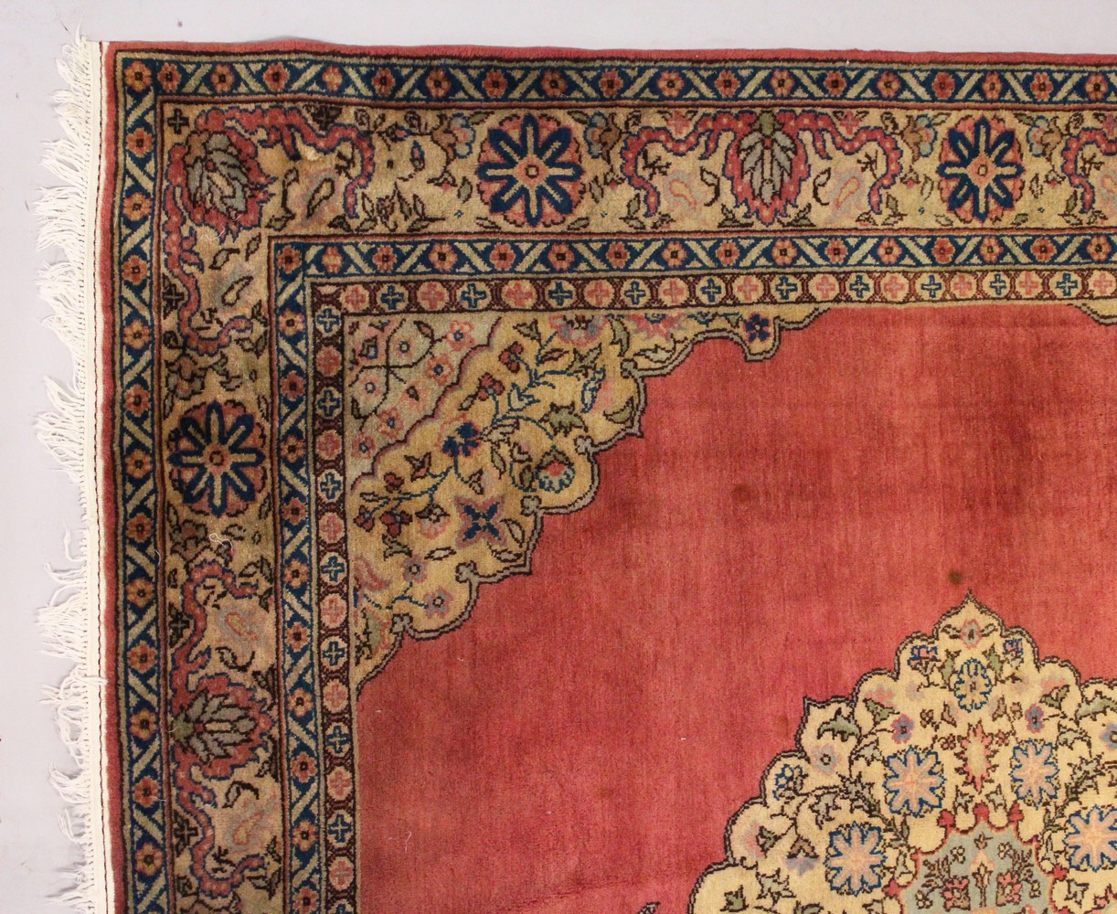 A PERSIAN CARPET, with rose ground, central motif, motifs to the border. 7ft 2ins x 7ft 4ins.