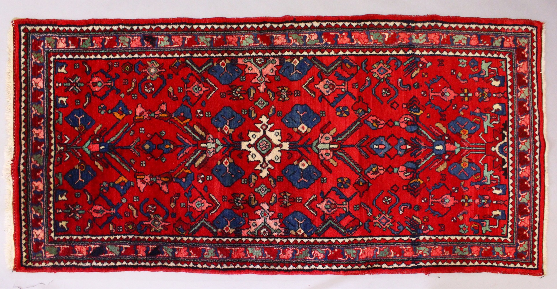 A PERSIAN RUG, with red and blue design. 6ft 8ins x 3ft 4ins.