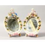 A SMALL PAIR OF DRESDEN TYPE OVAL PORCELAIN EASEL MIRRORS with cupids. 7ins high.