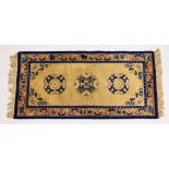 A CHINESE RUG, with beige ground, three central circular motifs and blue border. 5ft x 2ft 4ins.