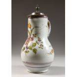 AN EARLY CONTINENTAL POTTERY LIDDED JUG, polychrome decorated with flowers. 12ins high.