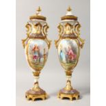 A PAIR OF SLENDER PORCELAIN VASES AND COVERS, with gilt metal mounts, the body painted with