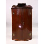 A GEORGE III MAHOGANY HANGING BOWFRONT CORNER CUPBOARD, the pair of doors enclosing three shelves.