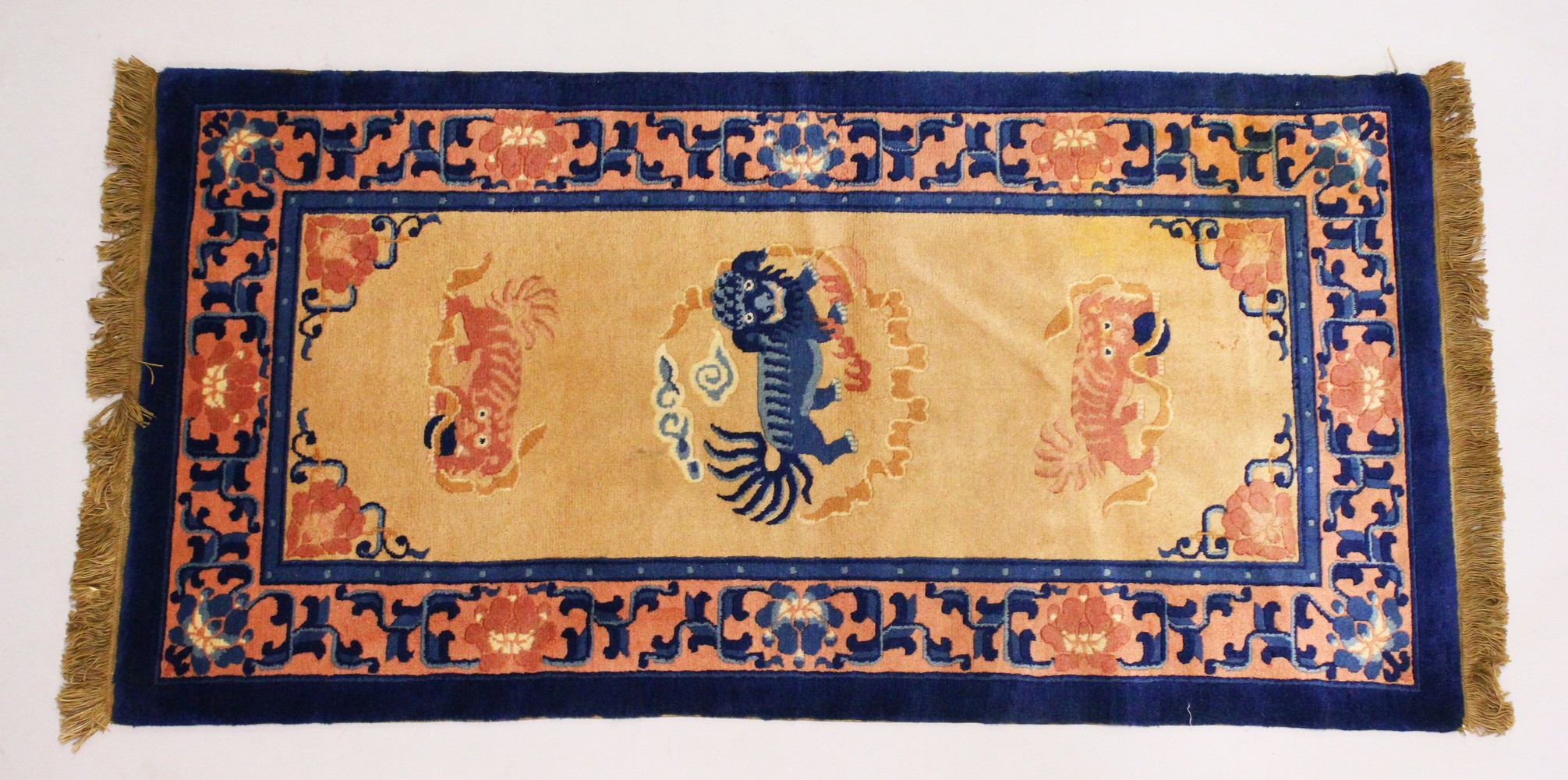 A CHINESE RUG, the centre with Dog of Fo motifs, beige ground and blue border. 5ft x 2ft 5ins.``