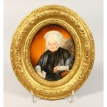 AN OVAL GILT FRAMED MINIATURE OF AN OLD LADY, sitting in a chair. 5ins x 4ins.