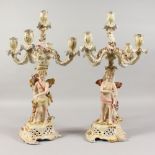 A PAIR OF DRESDEN DESIGN PORCELAIN FIVE-LIGHT CANDELABRA, with cupid supports. 17ins high.