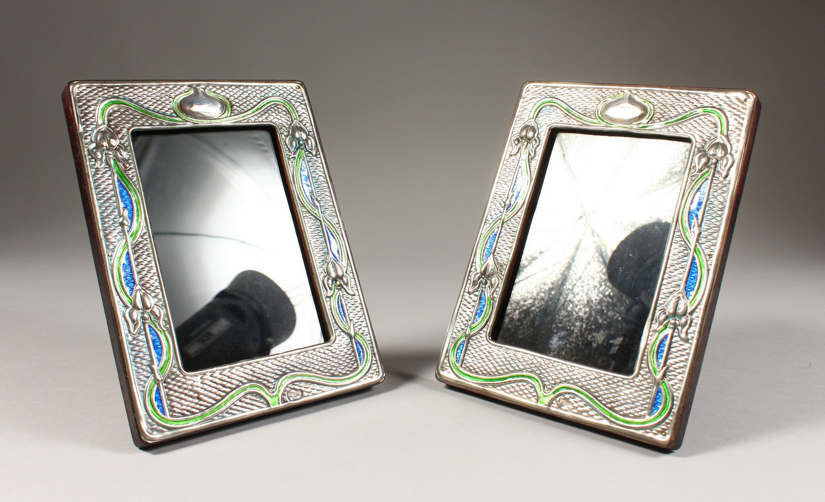 A PAIR OF ART NOUVEAU STYLE SILVER AND ENAMEL PHOTOGRAPH FRAMES. 8ins x 6.25ins.