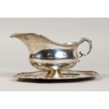 A HAMMERED SILVER GRAVY BOAT AND STAND (2).